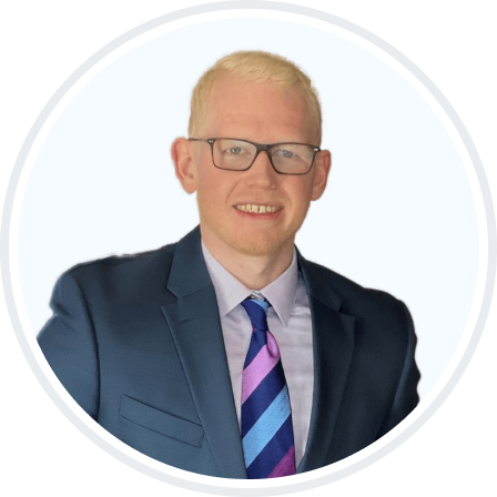 Headshot picture of Zeke, General Manager, smiling and wearing a blue suite with tie.